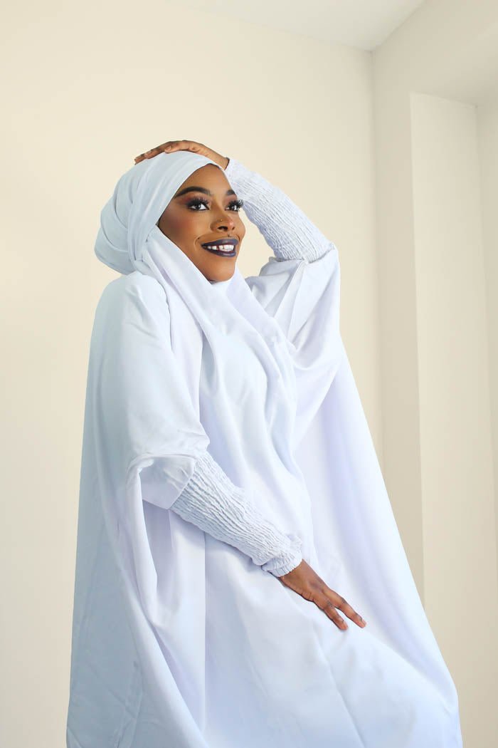 a womn is wearing white set jilbab